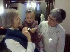 Baby Marguerite Marie embraces the Sister's cross on Vow Renewal Day