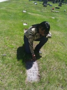 Constance kneels at her son, Dante's, grave.